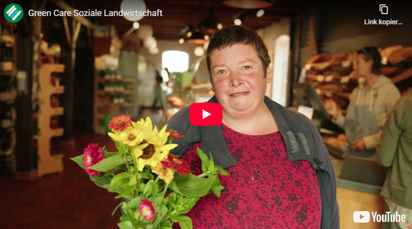 Ein Mensch mit Blumen davor und einem Youtubeplaybutton im Vordergrund